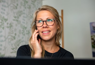 En kvinna som bär glasögon och ler mot kameran 
