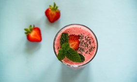 Ett glas med smoothie och jordgubbar 